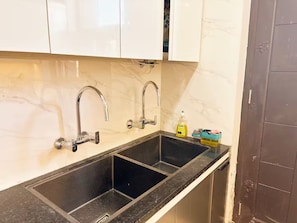 Una cocina con dos fregaderos, salpicadero de mármol y armarios.