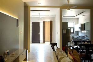 Habitación de hotel con cama, escritorio, silla, mesa de comedor y zona de cocina.