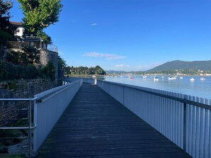 A wooden boardwalk leading to a body of water with boats, a stone wall, and a building with a balcony. - Good fountain, spacious apartment a stone's throw from the Spanish border (Hendaye)