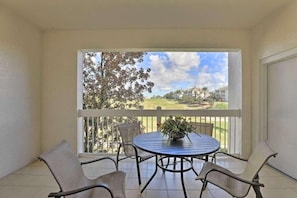 Ein Balkon mit rundem Tisch und Stühlen, einem Blumentopf und Blick auf eine Wohngegend.