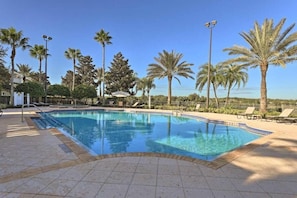 Ein Pool mit Palmen, Liegestühlen und blauem Himmel.