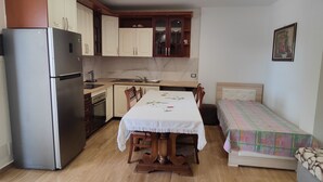 Una cocina compacta con refrigerador, estufa y mesa de comedor con sillas.