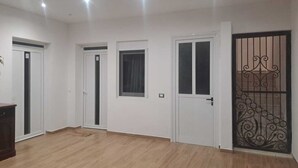 Una habitación con piso de madera, paredes blancas y tres puertas blancas.