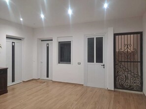 A room with wooden flooring, white walls, and three white doors.