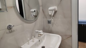 Un baño con lavamanos, espejo, secador de pelo y toallero.