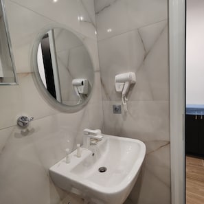 A bathroom with a sink, mirror, hairdryer, and a towel rack.