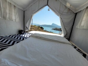 A tented room with a bed, a view of a lake, and mountains in the distance. - Glamp Of Dreams (Lonavala)