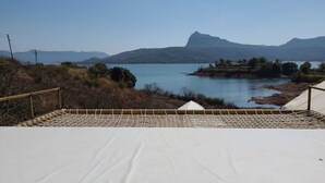Una escalera conduce a una plataforma blanca con vista a un lago y montañas al fondo.