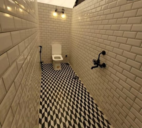 A bathroom with white tiled walls, a black and white checkered floor, and a white toilet.. Glamp Of Dreams