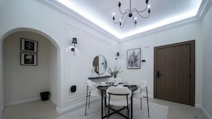 A dining area with a chandelier, a round table, and chairs. - Stylish Rawda Getaway | Comfortable 1BR Apartment (Jeddah)