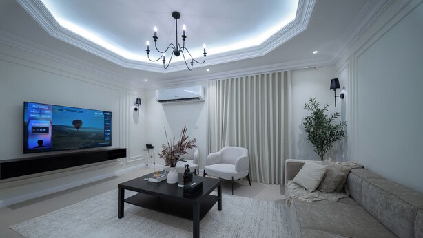 A modern living room with a flat-screen TV, a coffee table, a sofa, and a chandelier. - Stylish Rawda Getaway | Comfortable 1BR Apartment (Jeddah)