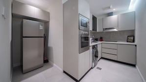 A modern kitchen with a refrigerator, oven, microwave, and sink. - Stylish Rawda Getaway | Comfortable 1BR Apartment (Jeddah)