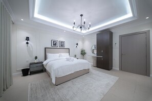 Ein modernes Schlafzimmer mit einem großen Bett, Nachttischlampen, einer Kronleuchter und einem Kleiderschrank.