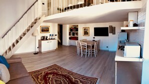 Un grand espace de vie comprenant un escalier, une table à manger et un coin cuisine.
