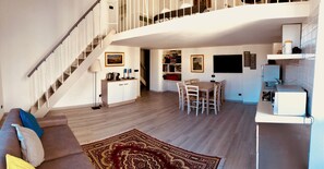 Ein geräumiger Wohnbereich mit Treppe, einem Esstisch und einer Küchenzeile.