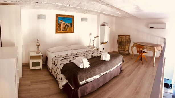 Une chambre à coucher comprenant un lit, une table de chevet, une lampe, un appareil de climatisation et un tableau accroché au mur.