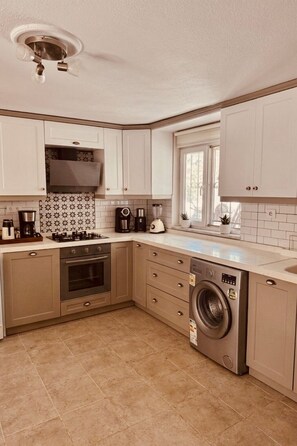 A kitchen with white cabinets, a built-in oven, a dishwasher, and a window.