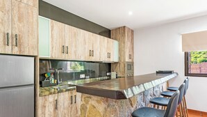 A kitchen with a stone island, bar stools, and a refrigerator. - Ifaya Farm (San Miguel)
