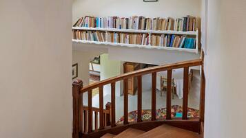 Un escalier avec une rampe en bois menant à un palier où se trouve une bibliothèque remplie de livres.