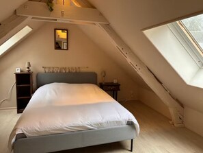 Una camera da letto con un letto, un comodino, una lampada, uno specchio e una finestra.