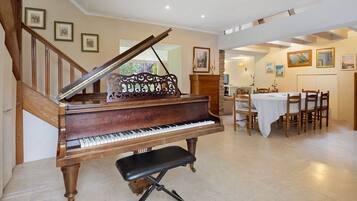 A grand piano in a spacious room with a dining area and a staircase.