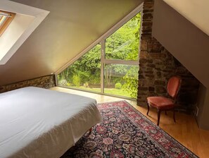 Una camera da letto con una grande finestra, un letto, una sedia e un camino.