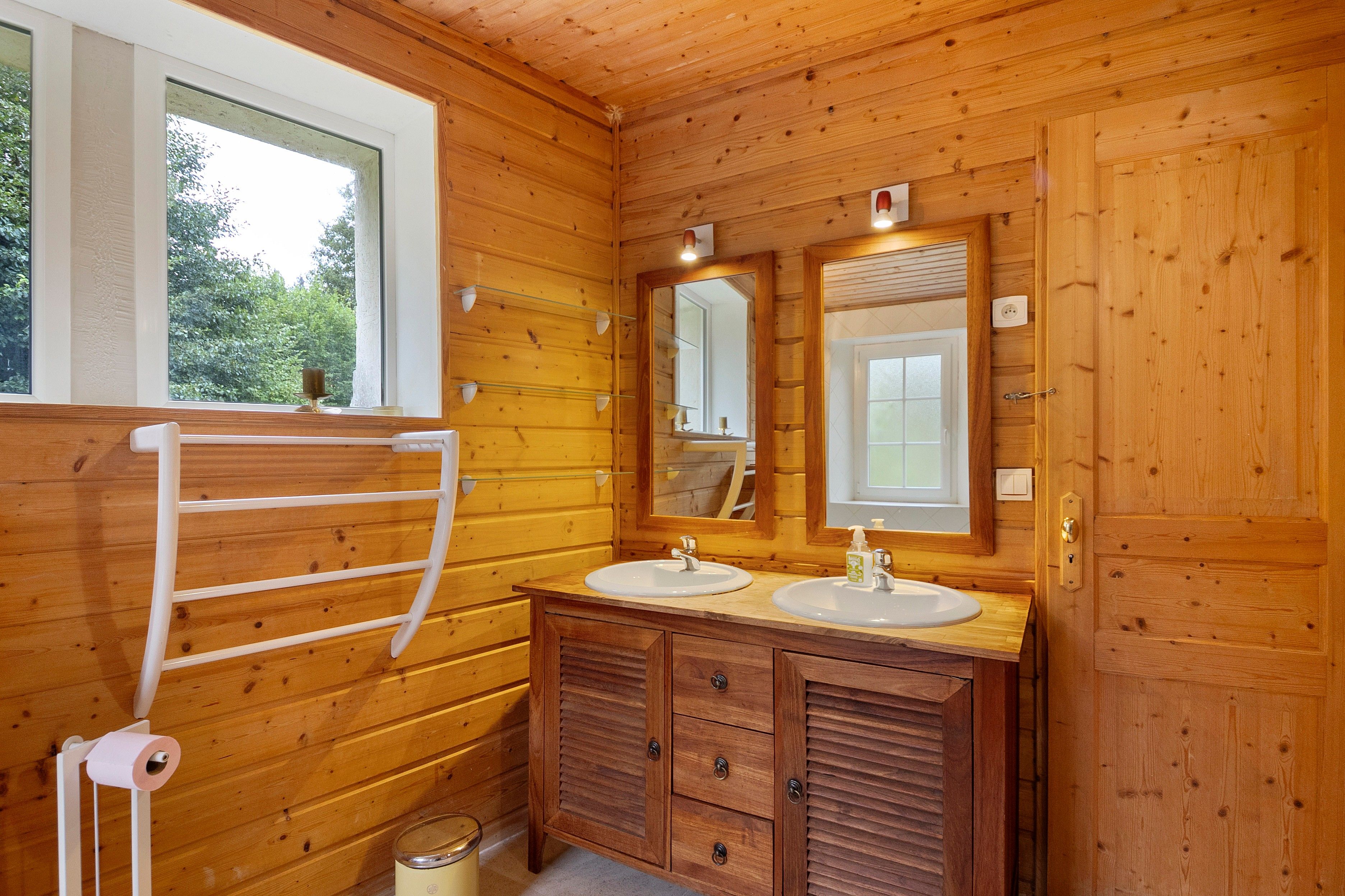 Une salle de bain en bois avec deux lavabos, un miroir et un porte-serviettes.