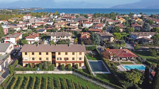 A residential area with houses, a swimming pool, and a view of the sea. - Apollo 19 by Wonderful Italy (Sirmione)