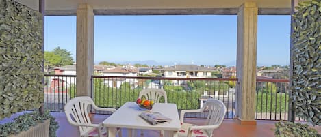 A balcony with a table, chairs, a fruit bowl, and a magazine.