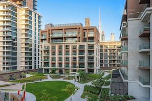 Ein modernes Apartmenthaus mit mehreren Balkonen, einem Dachgarten und Blick auf die Skyline der Stadt.