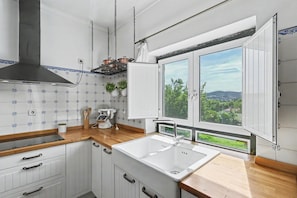 A kitchen with a large window, white cabinets, and a stainless steel range hood.