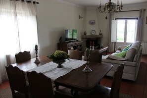 Et spiseområde med et træbord, stole, et fjernsyn og en pejs.