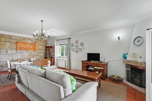 A living room with a sofa, a wooden coffee table, a television, a fireplace, and a stone wall.