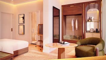 A hotel room with a bed, a TV, a seating area with a table, and a wardrobe with a mirror.