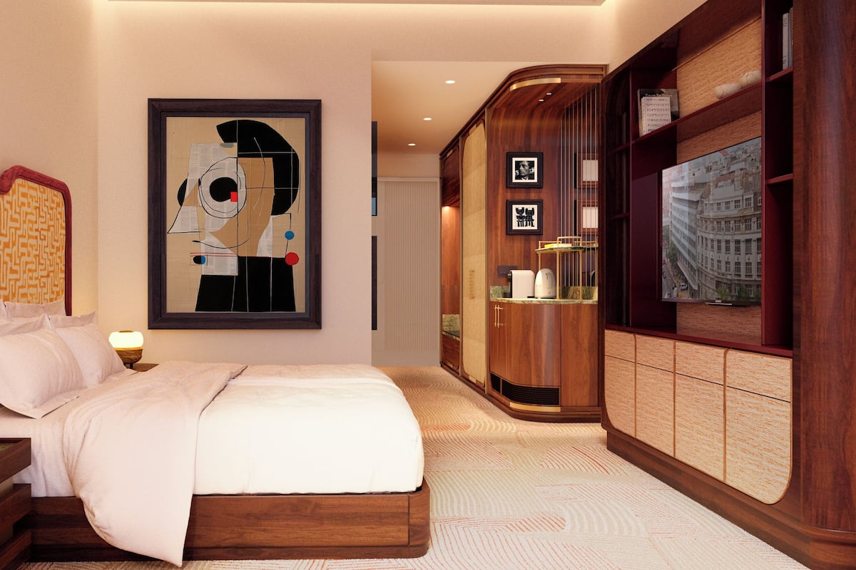 Habitació d'hotel amb llit, una nit, una làmpada, un quadre abstracte emmarcat, un armari de fusta i un televisor.