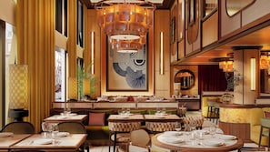 Interior de restaurante con techos altos, paredes con diseño y una gran obra de arte abstracta.