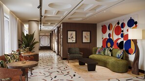 Een moderne hotel lobby met een geruit fauteuil, een groene bank, een ronde tafel en een vloer met een patroon.
