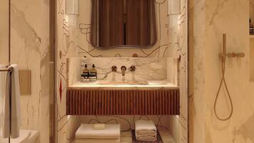 A bathroom with a marble floor, a sink with a wooden vanity, a mirror, and a shower area.