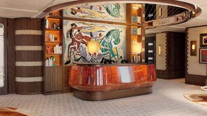 Um hall de entrada com uma mesa de recepção curva, estantes de livros e um grande mural abstrato.