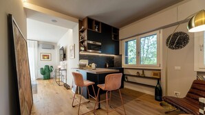 Una cocina moderna con suelo de madera, una barra con dos taburetes y un ventanal que proporciona luz natural.