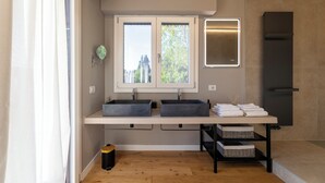 Un baño moderno con dos lavabos, un espejo, un perchero para toallas y ducha integrada.