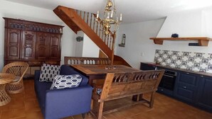Un coin repas avec une table et des chaises en bois, un canapé bleu, un meuble en bois et un escalier.
