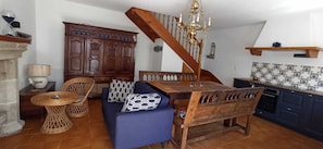 Ein Essbereich mit Holztisch und -stühlen, einem blauen Sofa, einem Holzschrank und einer Treppe.