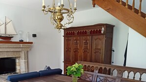 Un espace repas avec une table en bois, des bancs et un lustre.