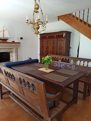 Ein Essbereich mit einem Holztisch, Bänken und einer Chandelier.