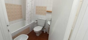 Ein Badezimmer mit Badewanne, Toilette, Bidet und Duschvorhang.