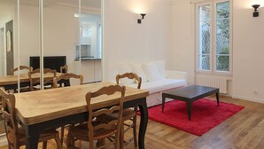 Ein modernes Wohnzimmer mit Essbereich, weißen Wänden und einem großen Spiegel.
