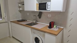 Eine kleine Küche mit Waschmaschine, Mikrowelle und Spüle.