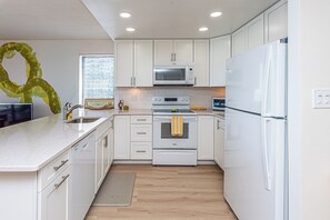 A modern kitchen with white cabinets, a microwave, oven, and refrigerator. - Beautifully Renovated 2 Bedroom Ocean Front Condo! Fountainhead Towers 1201 (Ocean City)
