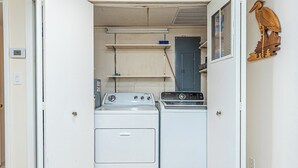 Una lavanderia con due lavatrici, una porta blu e una decorazione a forma di uccello in legno.